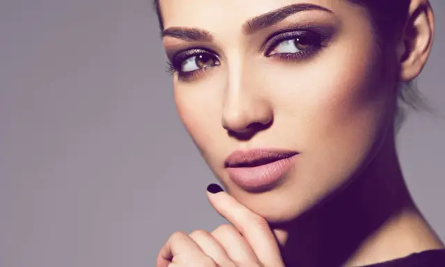 Ein Porträt einer Frau mit **smokey eyes dezent**. Ihre Augen sind von einem sanften, rauchigen Lidschatten umrahmt, der ihre braunen Augen betont.