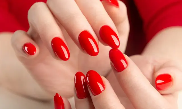 Hände mit leuchtend roten Nägeln, die die "red nail theory" verkörpern. Die glänzende Maniküre strahlt Selbstbewusstsein aus.