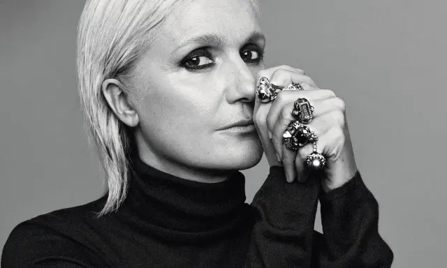 Maria Grazia Chiuri, mit markantem Make-up und vielen Ringen, blickt nachdenklich in die Kamera.
