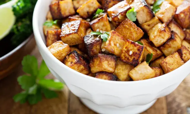 Knusprig gebratene Tofuwürfel in einer weißen Schüssel. Sie sehen lecker aus und man fragt sich, wie schmeckt tofu, wenn er so zubereitet wird.