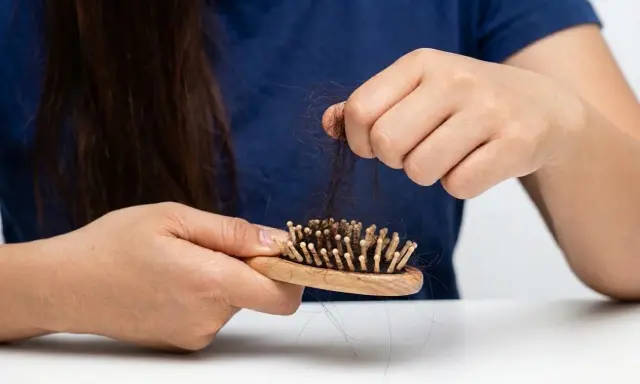 Besorgte Hände halten eine Bürste mit vielen Haaren. Was tun gegen Haarausfall? Informationen zu Ursachen und Behandlung.