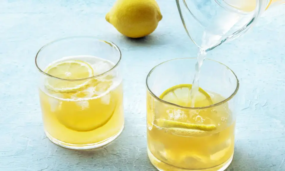 Erfrischendes zitronenwasser morgens wird in Gläser mit Eis und Zitronenscheiben gegossen.
