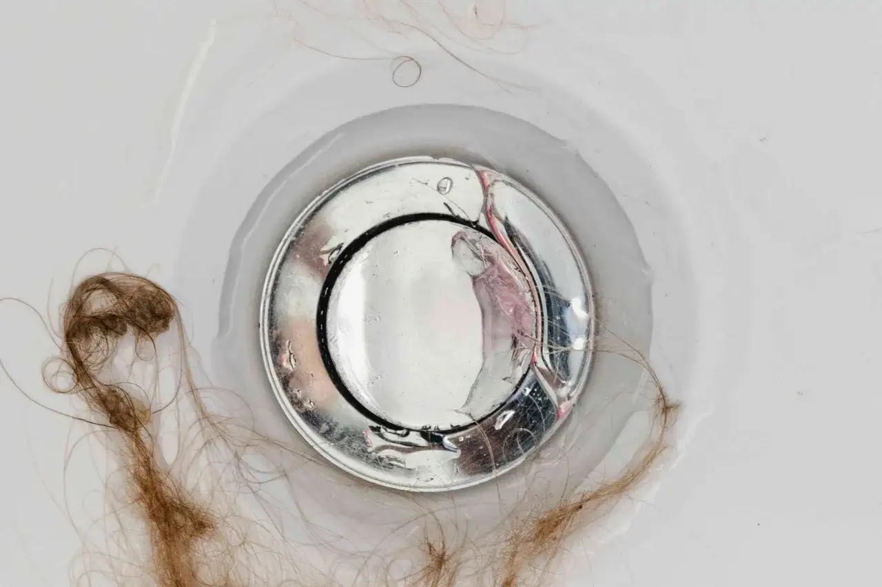 Haarausfall beim Haare waschen: Haarb&uuml;schel sammeln sich im Waschbeckenabfluss.