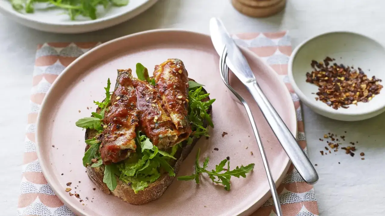 So isst man Sardinen aus der Dose: Auf Brot mit Avocado und Rucola, &uuml;bergossen mit Tomatensauce und bestreut mit Chiliflocken.