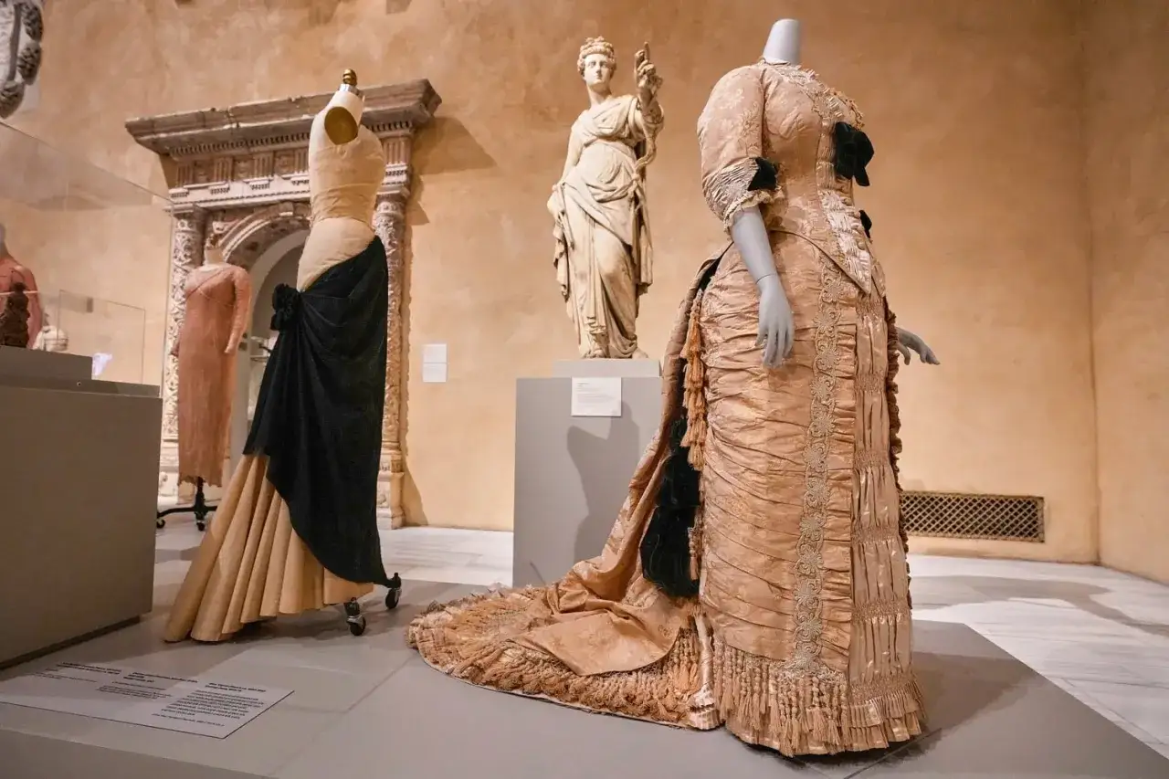 Historische Kleider, inspiriert vom Met Gala Thema, auf Schaufensterpuppen in einer Museumsausstellung.