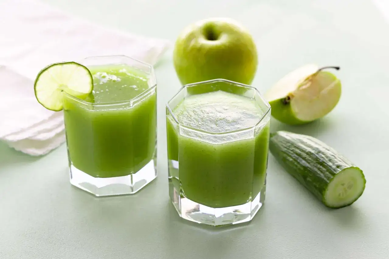 Zwei Gläser grüner Smoothie mit Gurke, Apfel und Limette. Die erfrischende gurkensaft wirkung macht diesen Drink zum perfekten Durstlöscher.