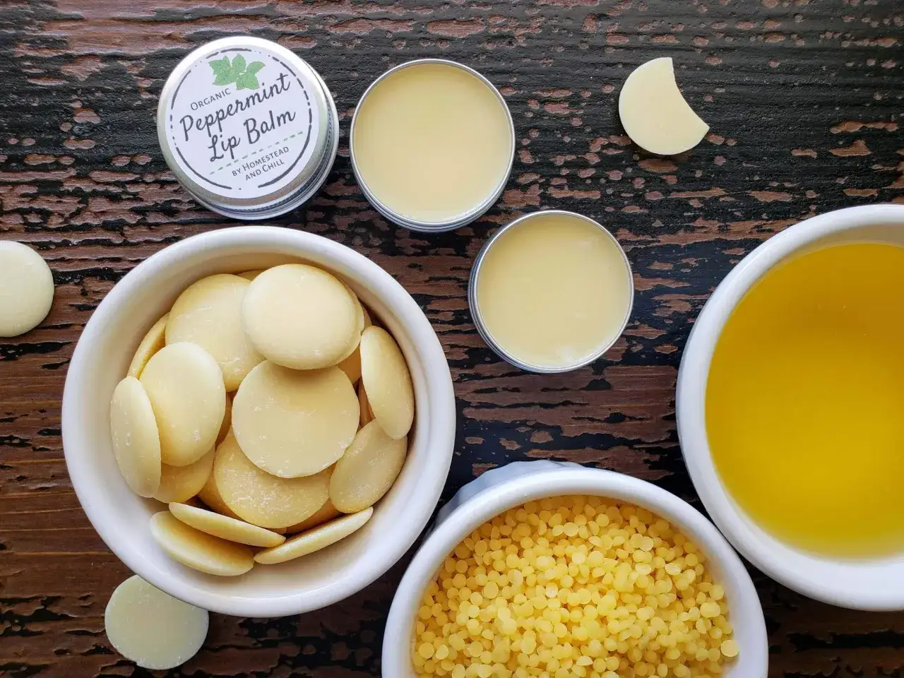Zutaten f&uuml;r Lippenbalsam selber machen: Kakaobutter, Bienenwachs, &Ouml;l und fertiger Lippenbalsam.