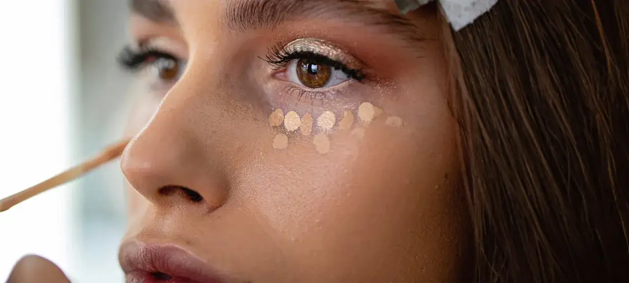 Make-up wird unter dem Auge aufgetragen, wo es sich in feinen Falten absetzt.