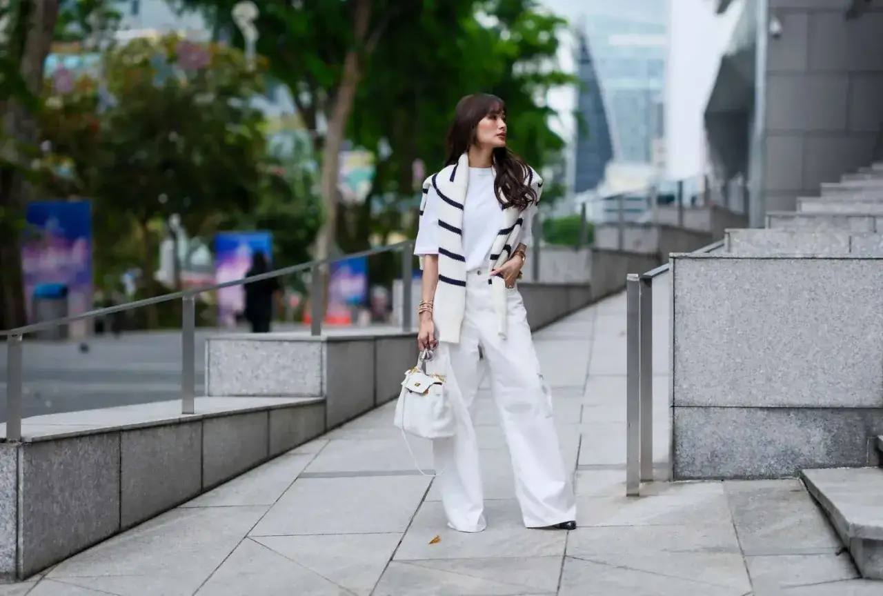 Chic Frau in wei&szlig;en Palazzo-Hosen und gestreiftem Cardigan. Ein perfektes Beispiel, wie man Palazzo-Hosen kombinieren kann f&uuml;r einen eleganten Look.