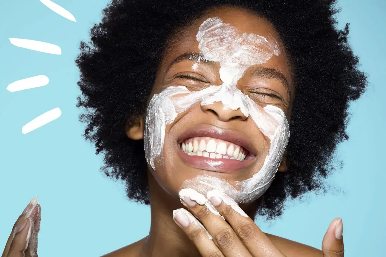 Gl&uuml;ckliche Frau mit einer Joghurt-Maske im Gesicht, die sich die Haut pflegt.