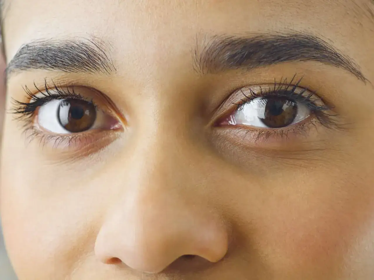 Nahaufnahme von braunen Augen und perfekt geformten Augenbrauen. So sehen Augenbrauen richtig formen aus.