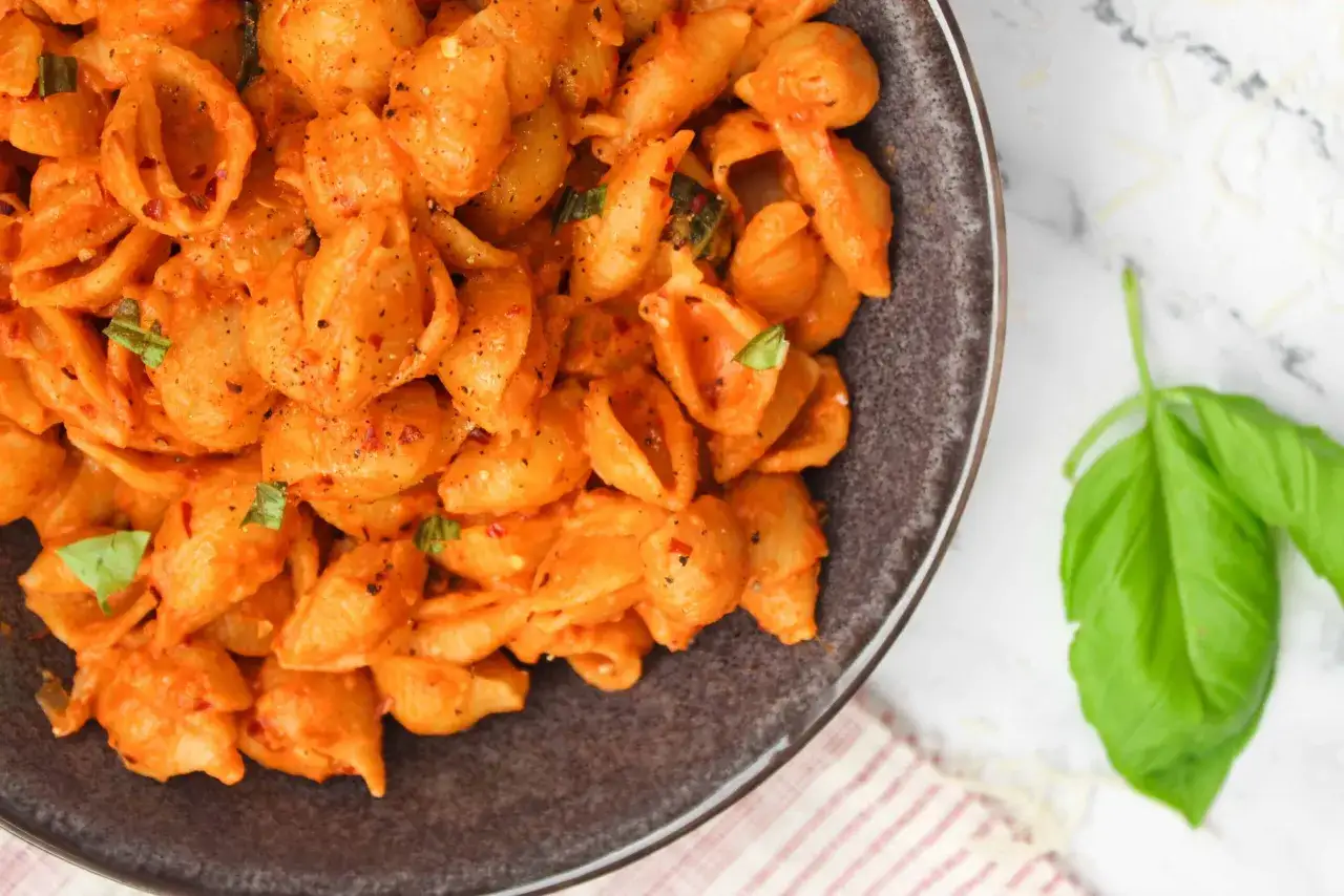 Gigi Hadid Pasta: Muschelnudeln in cremiger Tomatenso&szlig;e mit Basilikum und Chiliflocken, serviert in einer dunklen Sch&uuml;ssel.