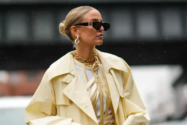Stylische Frau mit Dutt, Sonnenbrille und auffälligem Schmuck. Eine perfekte Frisur, die auch bei fettigen Haaren gut aussieht.