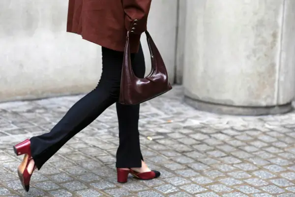 Schwarze Stoffhose kombinieren: Ein schicker Look mit brauner Tasche und zweifarbigen Slingback-Schuhen.